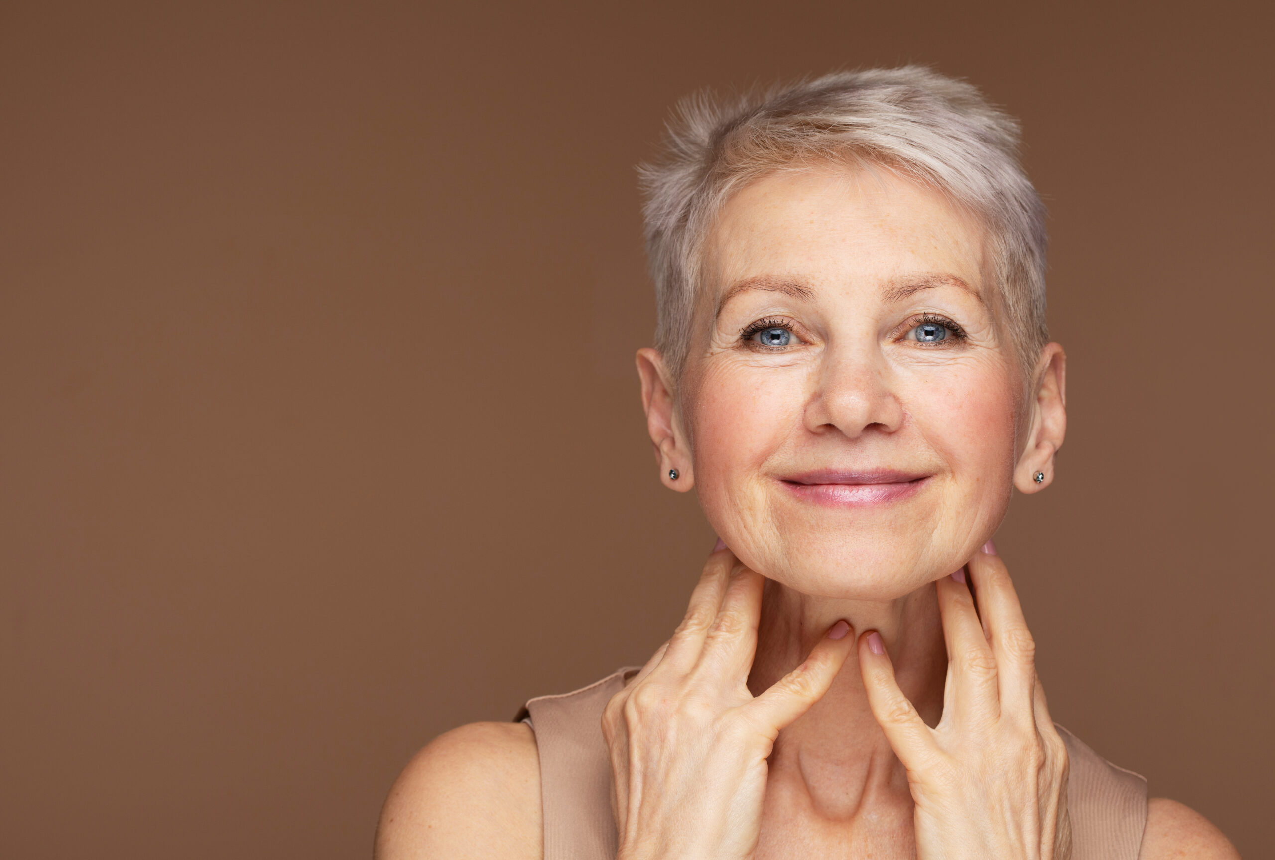 Beauty portrait of mature woman smiling with hand on face.